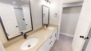 Bathroom with double vanity, tiled shower, and light tile patterned flooring