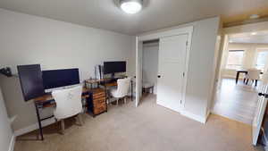 Carpeted home office featuring a textured ceiling and baseboards