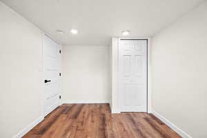 Empty room with a textured ceiling and dark wood-style floors