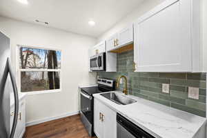 Kitchen with tasteful backsplash, stainless steel appliances, white cabinets, dark wood finished floors, and recessed lighting