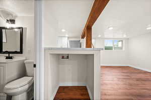 Bathroom with a textured ceiling, dark wood-style floors, vanity, recessed lighting, and beamed ceiling