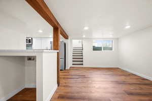 Basement featuring freestanding refrigerator, stairway, light wood-style floors, recessed lighting, and a textured ceiling