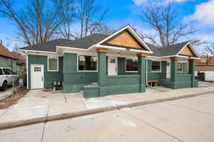 Craftsman-style home with roof with shingles, brick siding, and covered porch