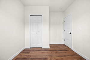 Unfurnished bedroom featuring dark wood finished floors and a closet
