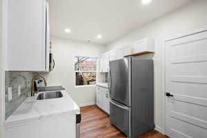 Kitchen with stainless steel appliances, tasteful backsplash, white cabinetry, dark wood finished floors, and recessed lighting
