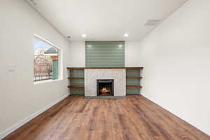 Unfurnished living room with dark wood-style floors, a tile fireplace, and recessed lighting
