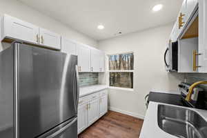 Kitchen featuring stainless steel appliances, tasteful backsplash, dark wood-style flooring, white cabinets, and recessed lighting