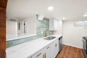 Kitchen featuring a textured ceiling, white cabinetry, dark wood-type flooring, decorative backsplash, and light stone counters