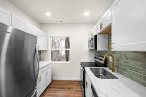Kitchen featuring stainless steel appliances, light stone counters, white cabinetry, and recessed lighting