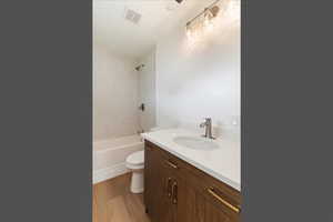 Full bathroom featuring light wood-style floors, a textured ceiling, vanity, and tub / shower combination