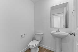 Half bath with dark wood-type flooring and baseboards