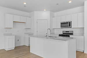 Kitchen with white cabinetry, recessed lighting, light wood-style flooring, a center island with sink, and stainless steel appliances
