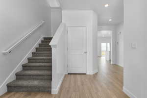 Stairs featuring wood finished floors and recessed lighting