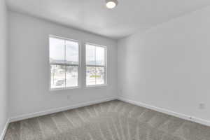 Carpeted empty room with baseboards and a textured ceiling
