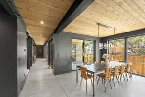 Dining room with concrete floors, a chandelier, a wooden ceiling with exposed beams, and recessed lighting