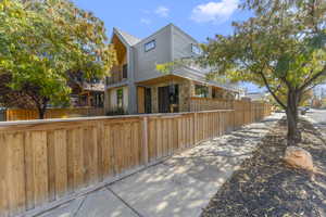 Back of property featuring a fenced front yard, stone siding, and a balcony