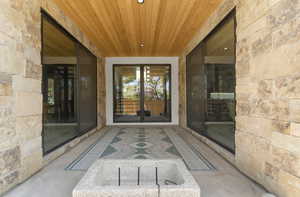 View of exterior entry with a patio area and stone siding
