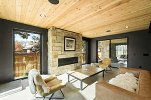 Living room featuring a fireplace, concrete floors, recessed lighting, and wood ceiling