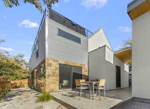 Rear view of house with stone siding, a patio area, and stucco siding