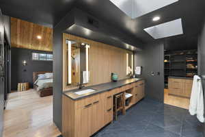 Bathroom featuring double vanity, ensuite bath, a skylight, dark wood-type flooring, and recessed lighting