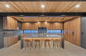 Kitchen featuring modern cabinets, a breakfast bar area, brown cabinetry, a spacious island, and backsplash