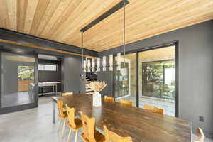Dining room with finished concrete floors, healthy amount of natural light, stairway, wooden ceiling, and a barn door