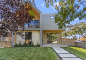 Rear view of property with a balcony, a patio, stucco siding, and stone siding