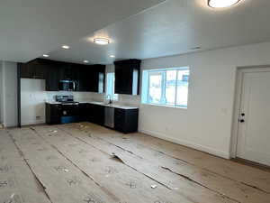 Kitchen featuring dark cabinets, light countertops, appliances with stainless steel finishes, and a textured ceiling