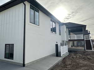 View of side of property featuring board and batten siding, stairway, and a patio