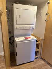 Laundry closet with light wood finished floors and stacked washer and clothes dryer