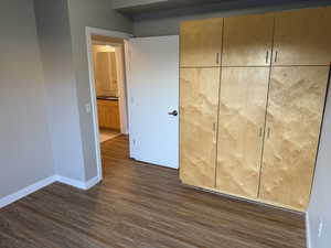 Unfurnished bedroom featuring dark wood-style flooring and baseboards