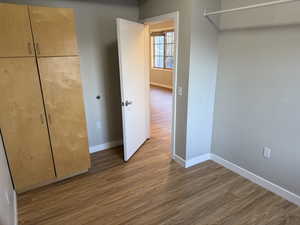 Unfurnished bedroom with wood finished floors and a closet
