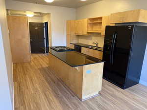 Kitchen featuring black appliances, open shelves, light brown cabinetry, and backsplash