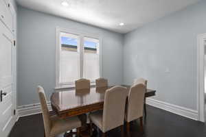 Dining space with dark wood-type flooring, a textured ceiling, and recessed lighting