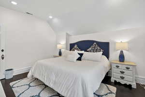 Bedroom with vaulted ceiling, dark wood-style flooring, and recessed lighting