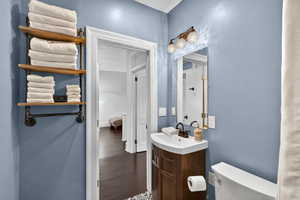 Half bath with a textured wall, dark wood-style floors, and vanity