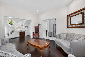 Living room featuring dark wood-style flooring, stairway, and recessed lighting