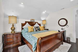 Bedroom with dark wood finished floors, vaulted ceiling, and recessed lighting