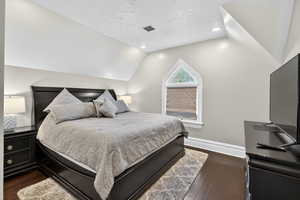 Bedroom with a textured ceiling, vaulted ceiling, dark wood-style floors, and recessed lighting