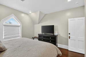 Bedroom with dark wood-type flooring, lofted ceiling, and recessed lighting
