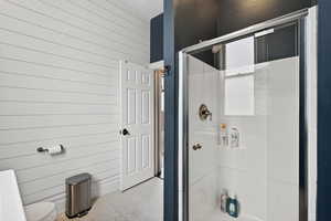 Full bath with a stall shower, wooden walls, and tile patterned floors