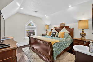 Bedroom with lofted ceiling, dark wood finished floors, a textured ceiling, and recessed lighting