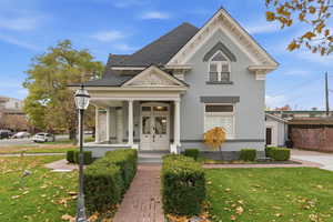 Neoclassical home featuring a front lawn, covered porch, roof with shingles, and crawl space