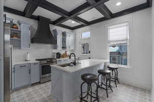 Kitchen featuring premium range hood, open shelves, stainless steel appliances, a breakfast bar area, and backsplash