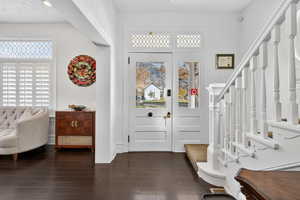 Foyer with stairway and dark wood-style flooring