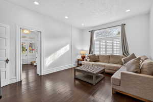 Living room featuring a textured ceiling, dark wood-style floors, recessed lighting, and french doors