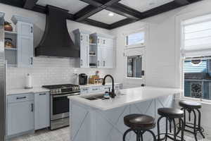 Kitchen with open shelves, custom range hood, gas stove, a kitchen bar, and beam ceiling