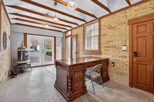 Home office featuring brick wall, french doors, and concrete floors