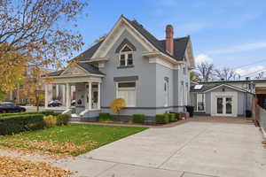 View of front of property with a porch, brick siding, roof with shingles, a front lawn, and a chimney