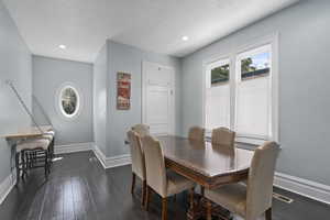 Dining space with dark wood finished floors, a textured ceiling, and recessed lighting